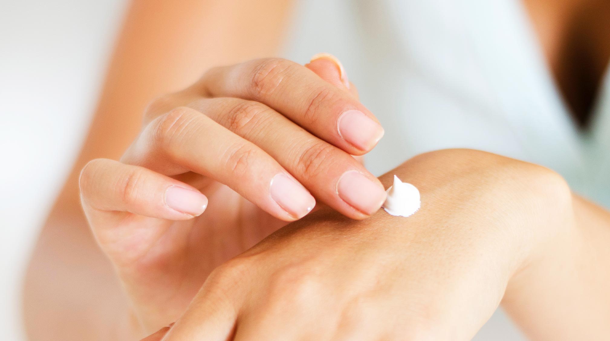 Hands applying mild lotion to skin