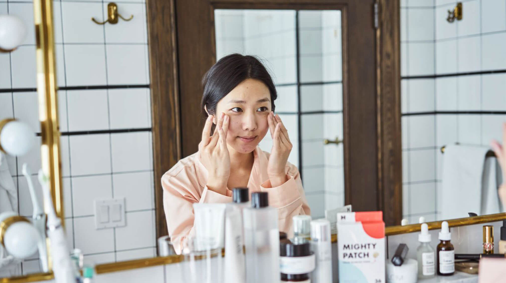Asian woman applying skincare to face