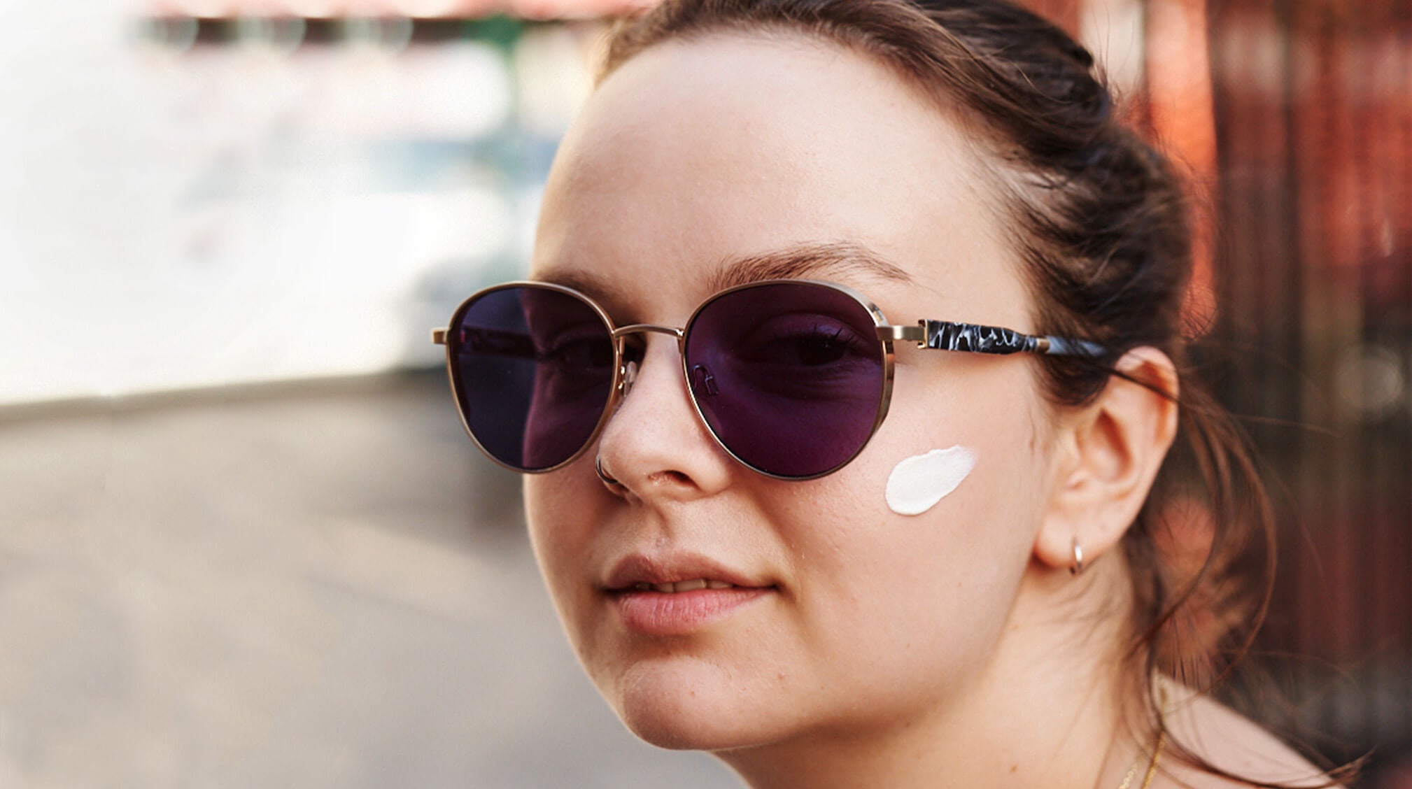 woman in sunglasses and with sunscreen on face
