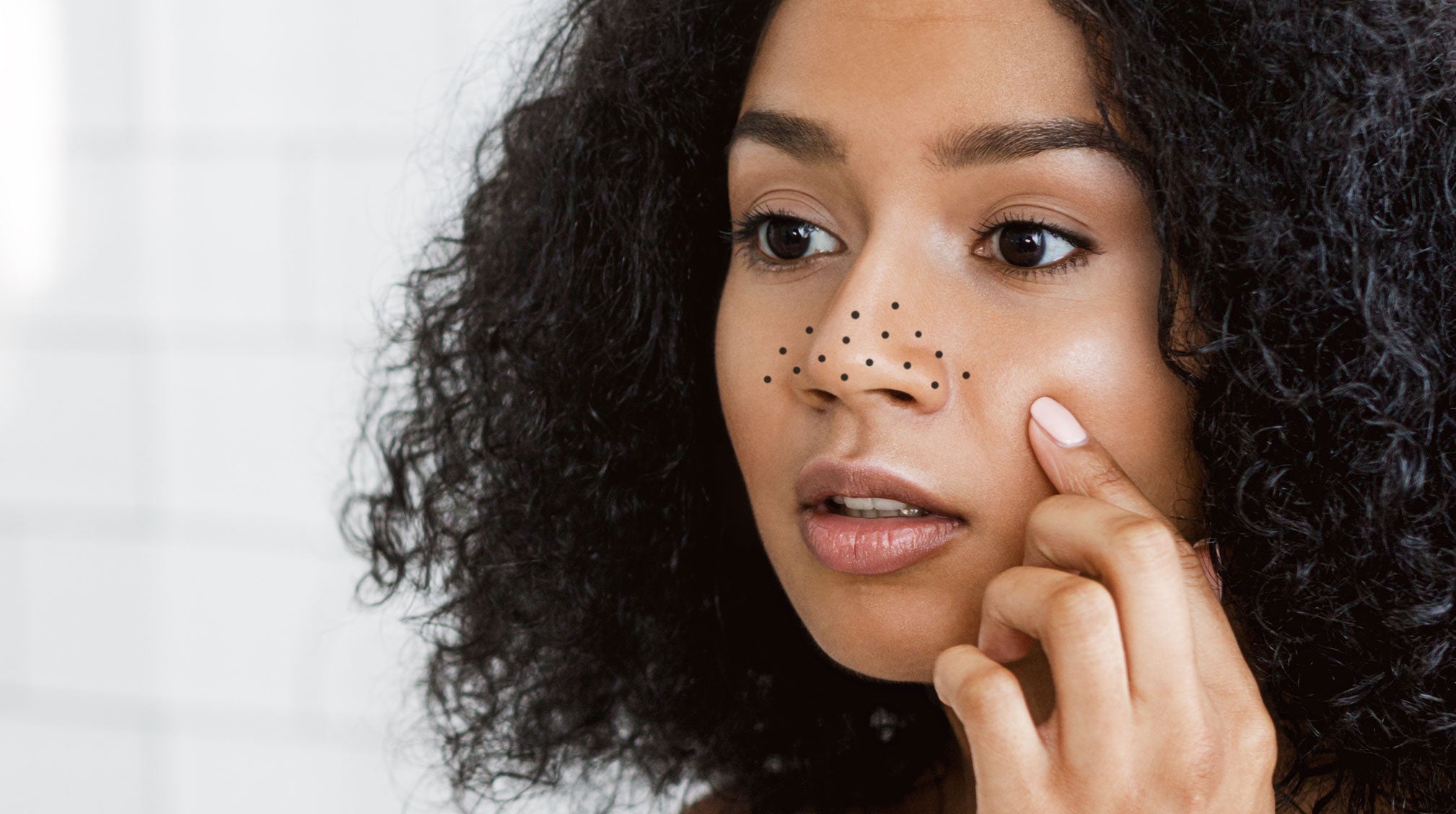 A woman looking at the blackheads on her nose