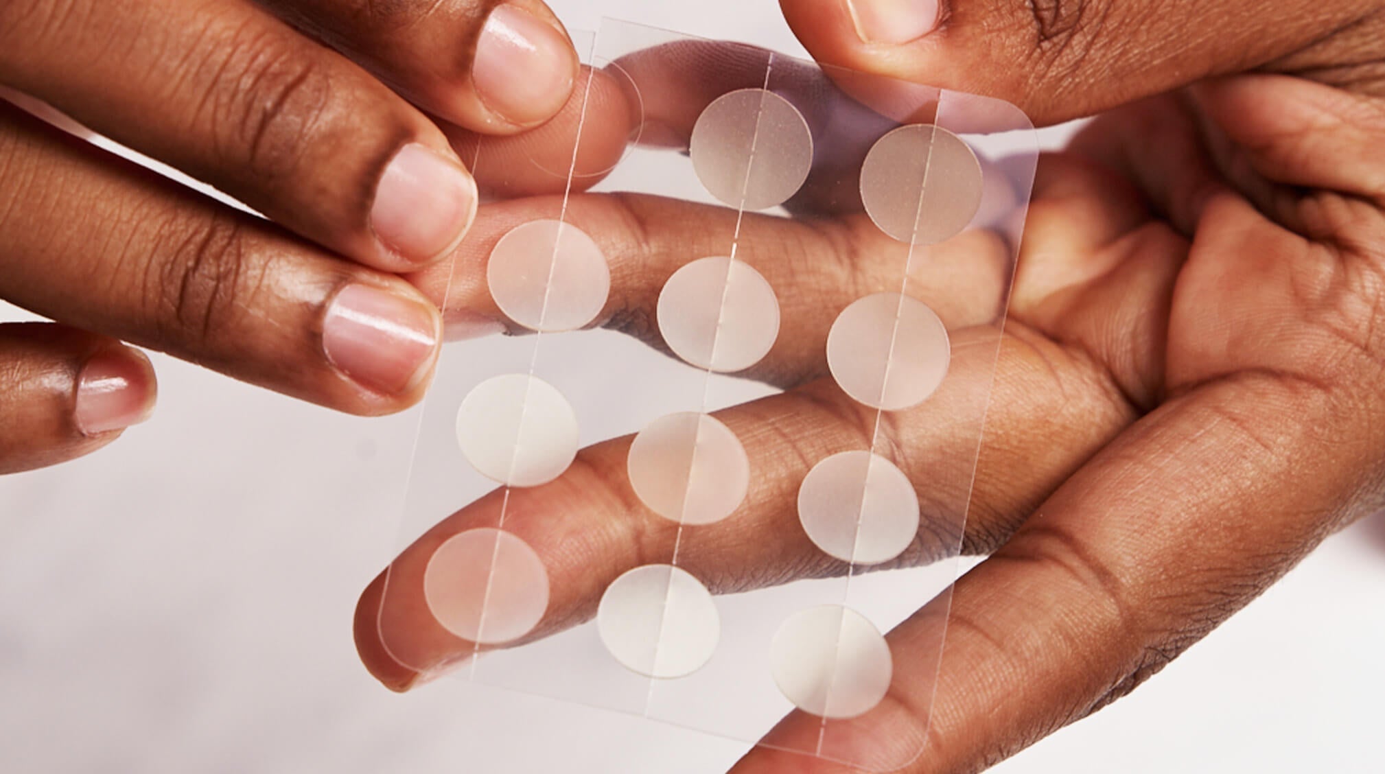 Lady removes pimple patch from container.