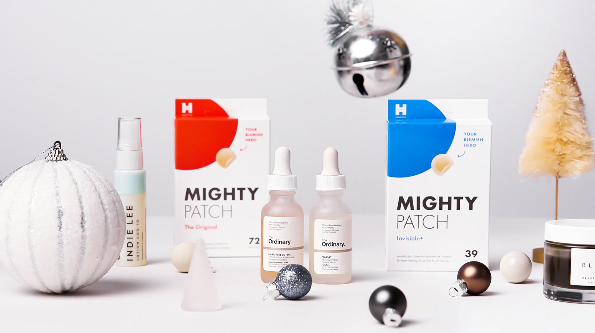 Acne care gifts from Hero Cosmetics, The Ordinary, Indie Lee and Herbivore next to Christmas ornaments