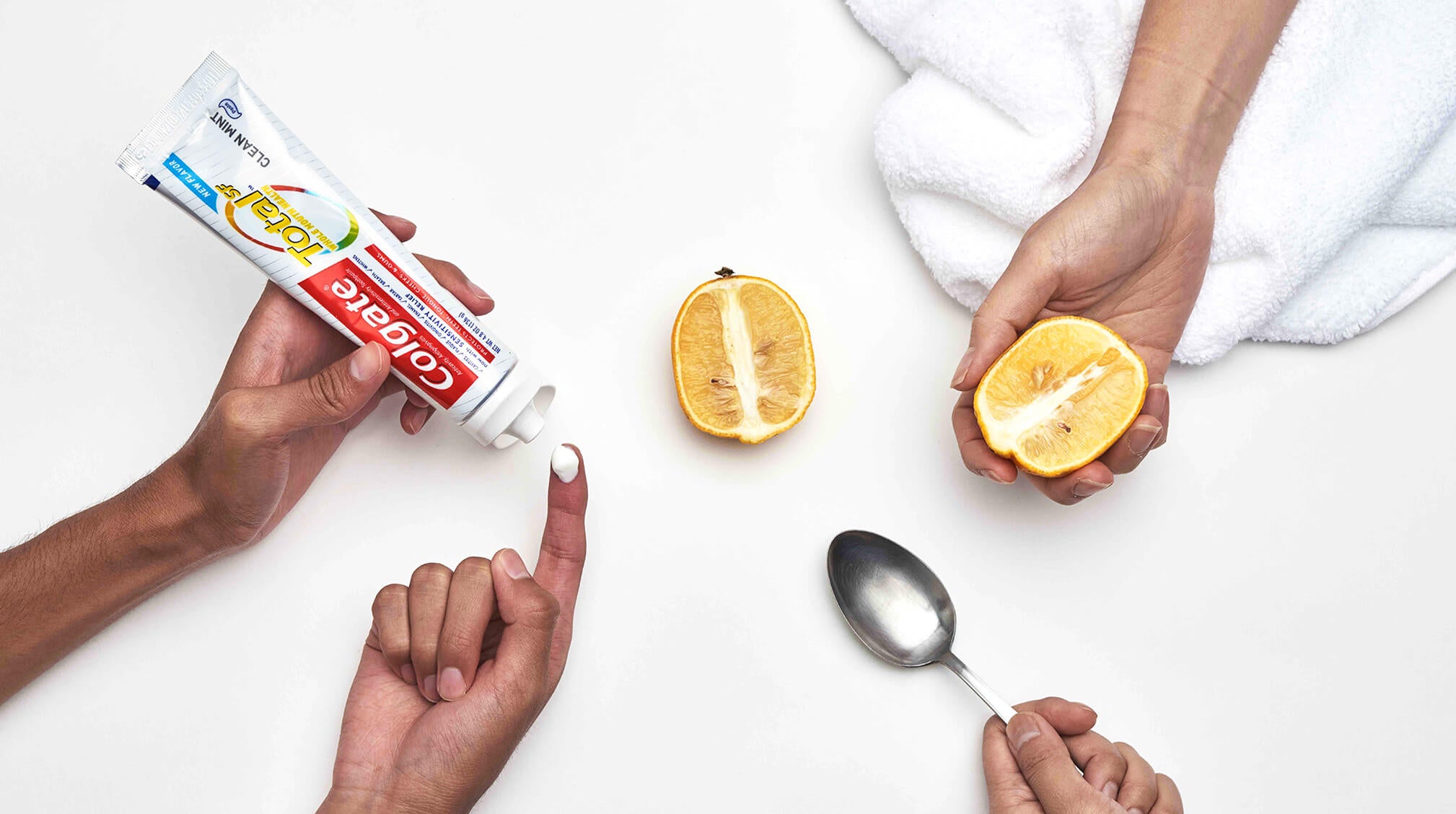 Hands holding toothpaste, lemons, and hot spoon.