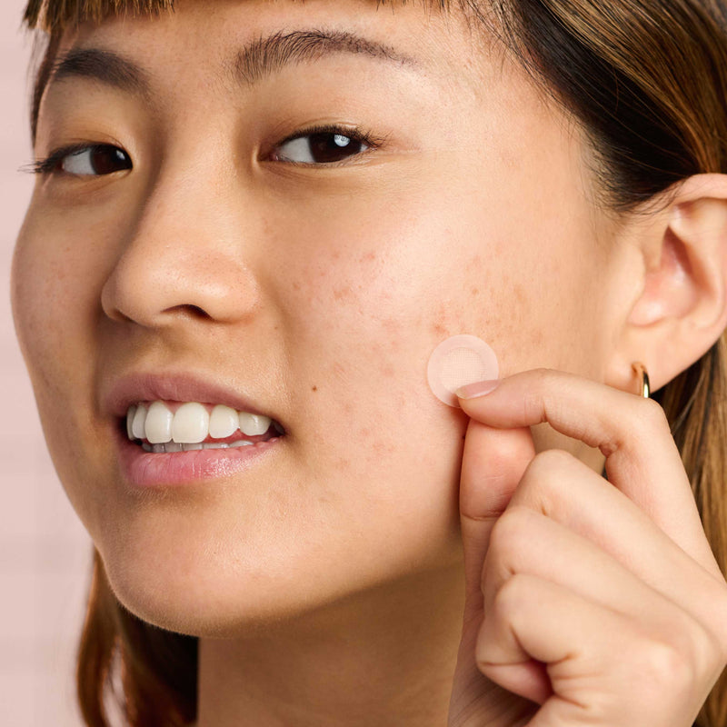 Woman applying a Mighty Patch™ for Dark Spots patch to her face.