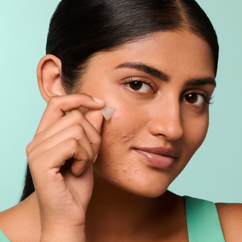 Woman applying a Mighty Patch™ for Early-Stage Blemishes patch to her face.