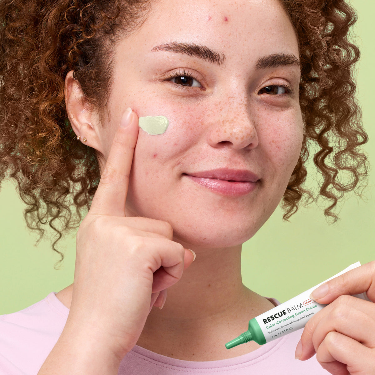 Woman applying Rescue Balm Red Correct to her face