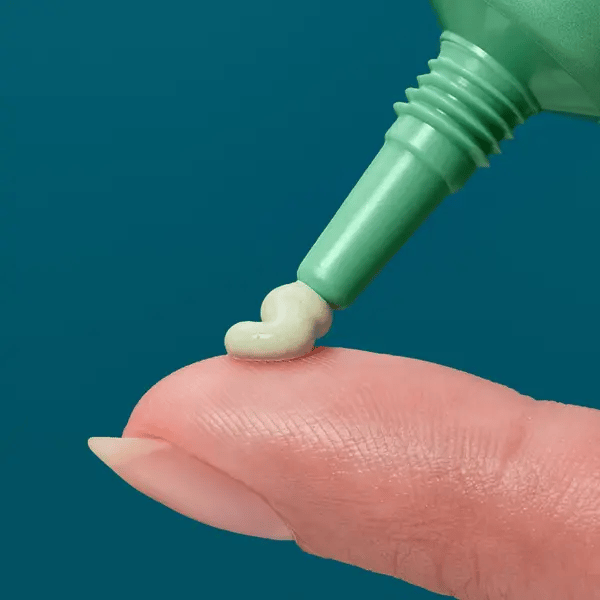Closeup of a small amount of Rescue Balm Red Correct cream to a person's finger