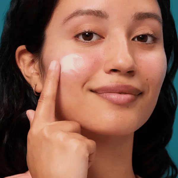 Woman applying Rescue Balm Red Correct to her face